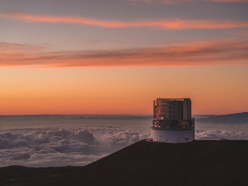 A breathtaking view of Mauna Kea Observatory against a vibrant sunset sky in Hawaii.
