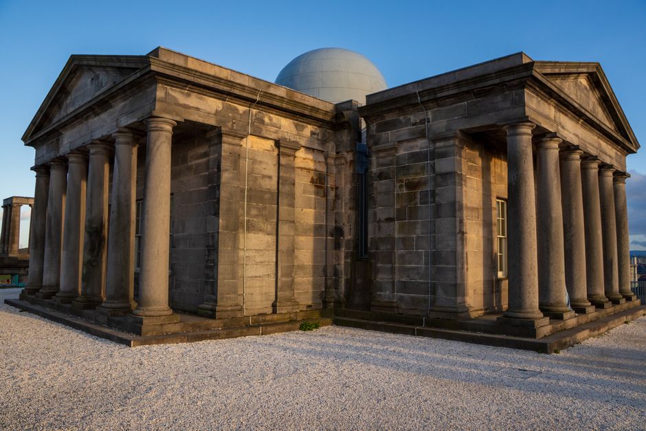 A grand stone observatory building with columns, captured at sunset.